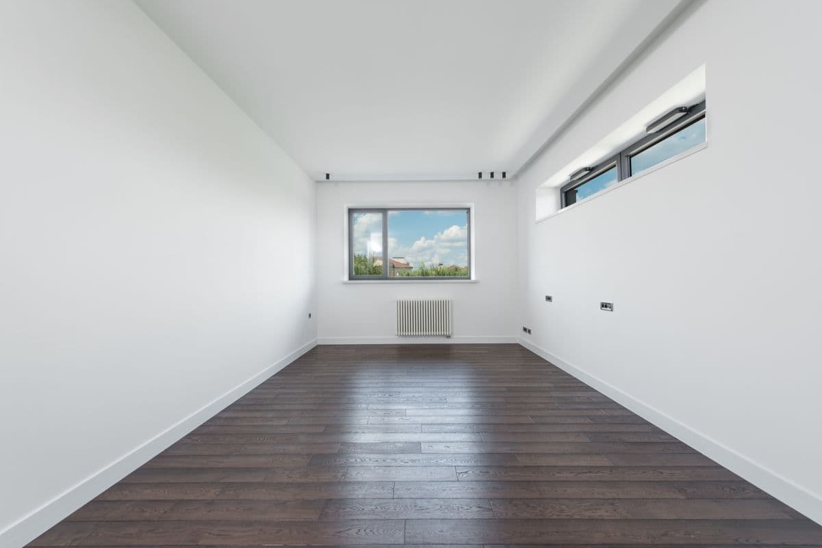 Empty room with white walls and dark flooring